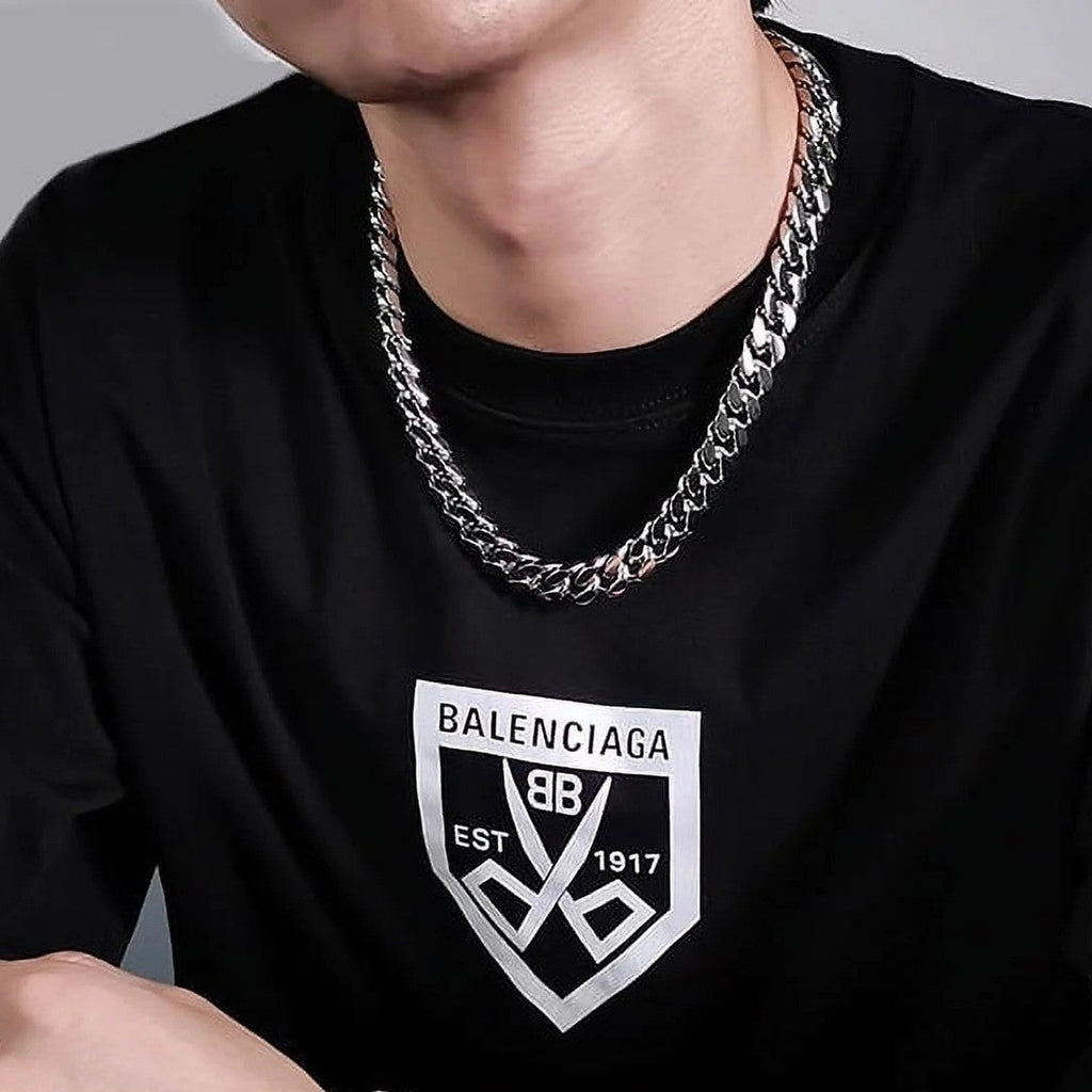 Person wearing a black t-shirt with a brand logo and silver chain necklace 