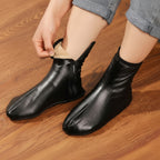 Person putting on black leather socks on a wooden floor