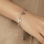 Silver butterfly bracelet on a wrist against a beige background