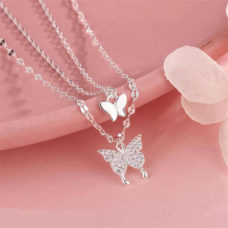 Silver butterfly necklace on a pink background