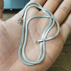 silver chain held in a hand with a blurred background