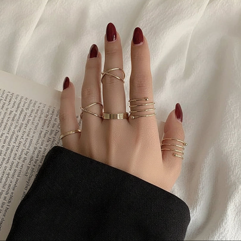 Hand with multiple gold rings on a white fabric background