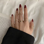 Hand with multiple gold rings on a white fabric background